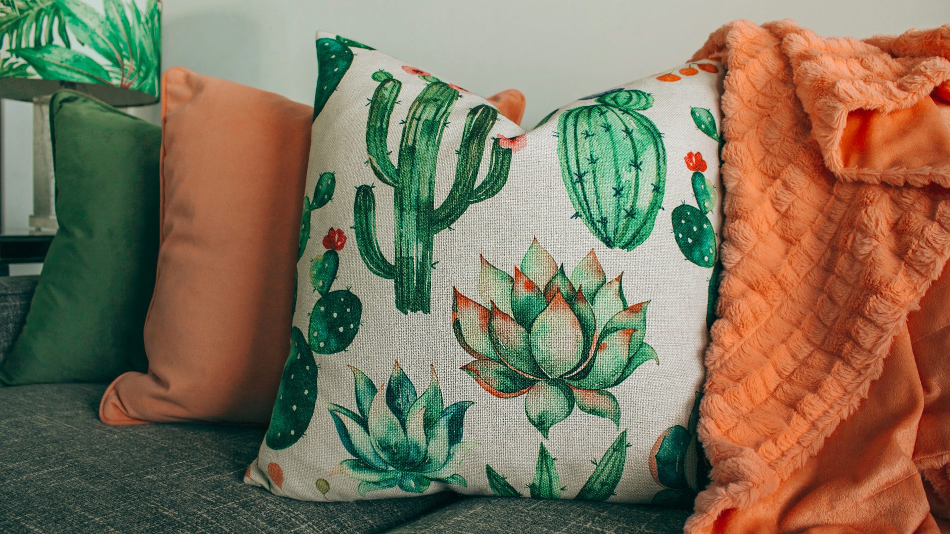 three green, orange, and white throw pillows on sofa